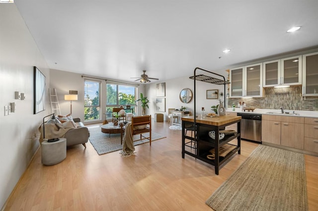 kitchen featuring dishwasher, light brown cabinets, light hardwood / wood-style floors, and tasteful backsplash