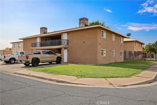 exterior space with central AC unit, a lawn, and a balcony