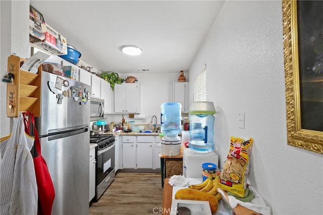 kitchen with white cabinetry, hardwood / wood-style flooring, stainless steel appliances, and sink