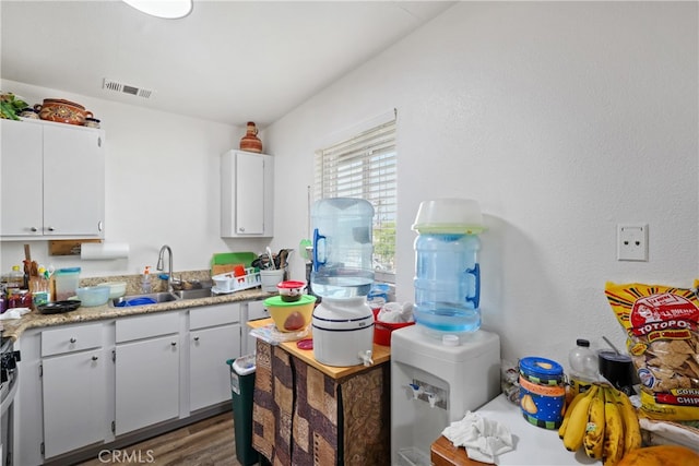 kitchen featuring dark hardwood / wood-style flooring, sink, stainless steel range, and white cabinets