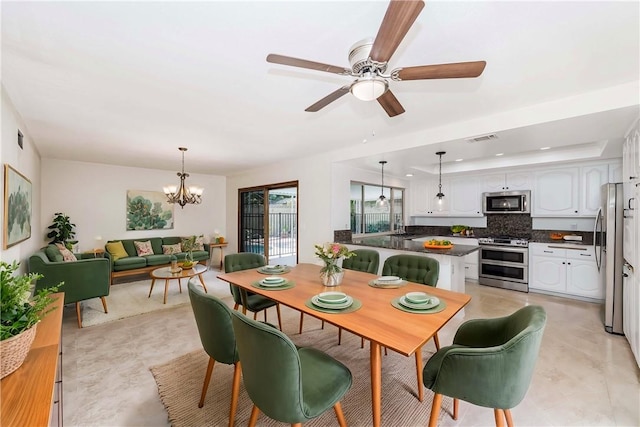 dining room with ceiling fan with notable chandelier and a raised ceiling