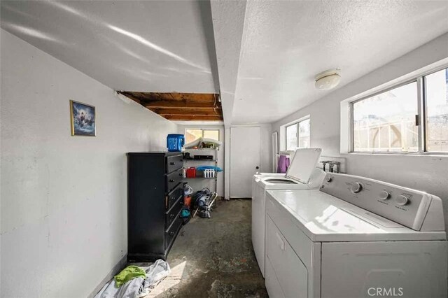 clothes washing area with washer and dryer and a textured ceiling