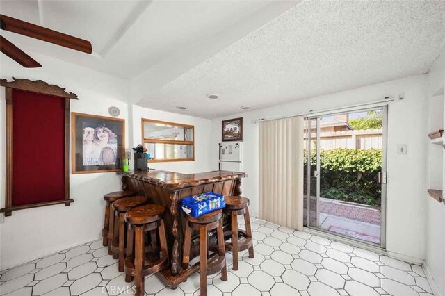 dining area with bar area and a textured ceiling