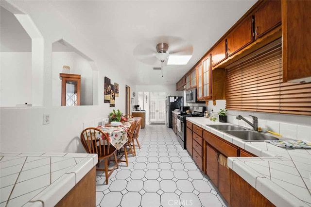 kitchen featuring sink, tile countertops, ceiling fan, and appliances with stainless steel finishes