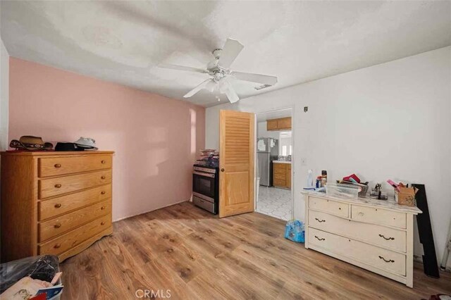 bedroom featuring light hardwood / wood-style flooring, stainless steel refrigerator, and ceiling fan