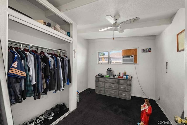 spacious closet with dark colored carpet, a wall unit AC, and ceiling fan