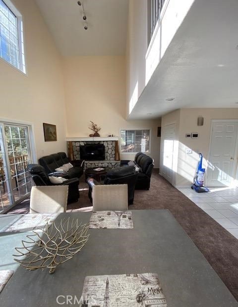 carpeted living room featuring a fireplace, a high ceiling, and a wealth of natural light