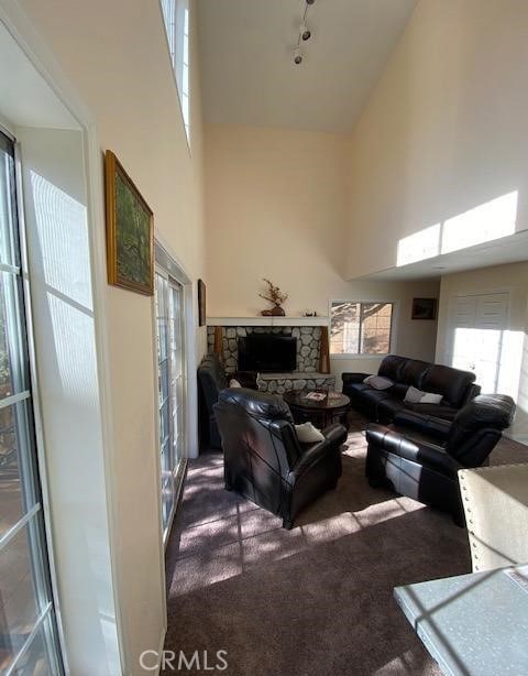 carpeted living room featuring a high ceiling and a stone fireplace