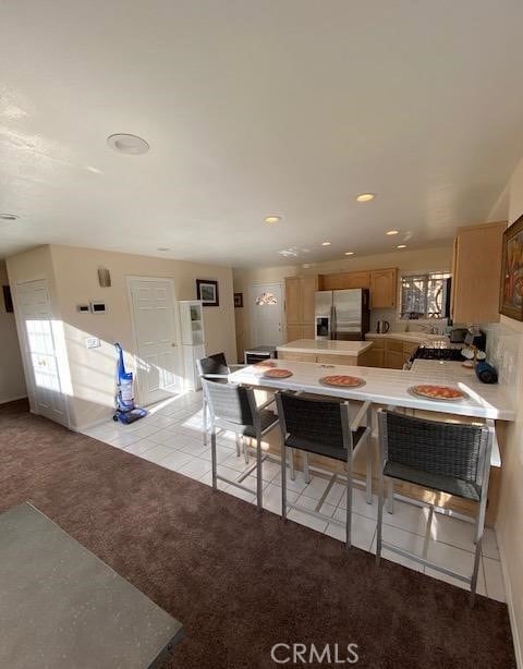 kitchen featuring kitchen peninsula, light colored carpet, and stainless steel refrigerator with ice dispenser