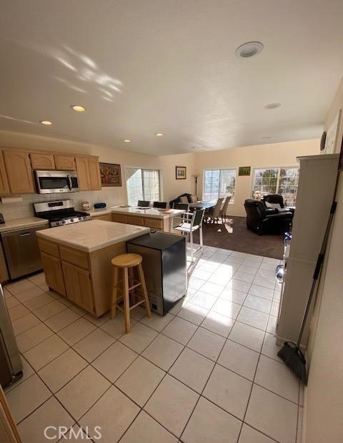 kitchen with plenty of natural light, appliances with stainless steel finishes, a center island, and a breakfast bar