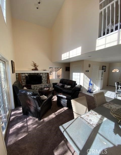 living room with a towering ceiling, a fireplace, and carpet