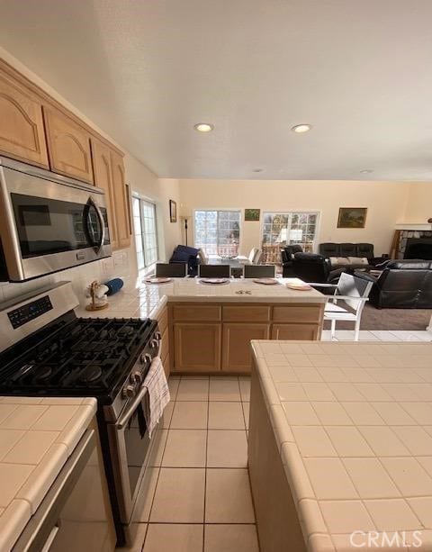 kitchen featuring light tile patterned floors, light brown cabinets, appliances with stainless steel finishes, and tile countertops