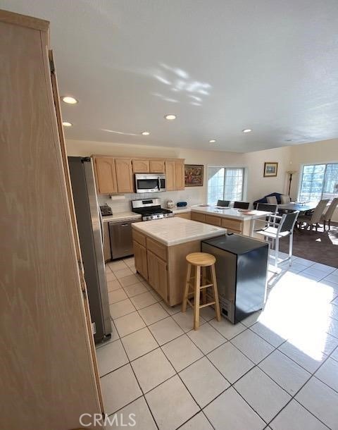 kitchen featuring appliances with stainless steel finishes, plenty of natural light, a breakfast bar area, and a center island