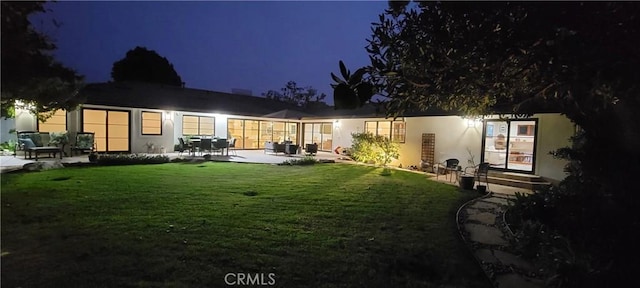 back house at twilight with a yard and a patio area