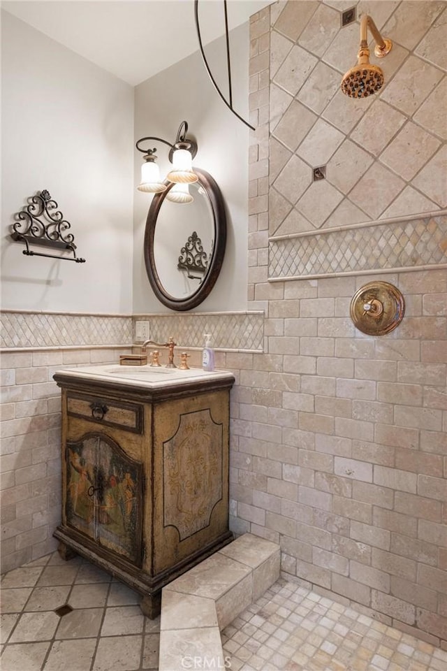 bathroom with a tile shower, vanity, and tile walls