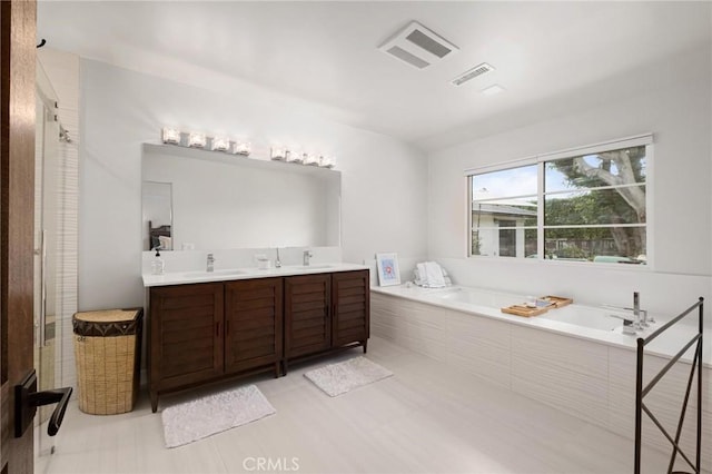 bathroom featuring tiled tub, tile patterned flooring, and vanity