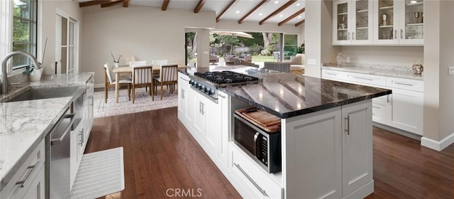 kitchen featuring light stone countertops, white cabinetry, a center island, stainless steel appliances, and sink