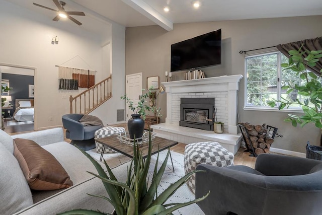 living room with ceiling fan, a brick fireplace, vaulted ceiling with beams, and light hardwood / wood-style floors