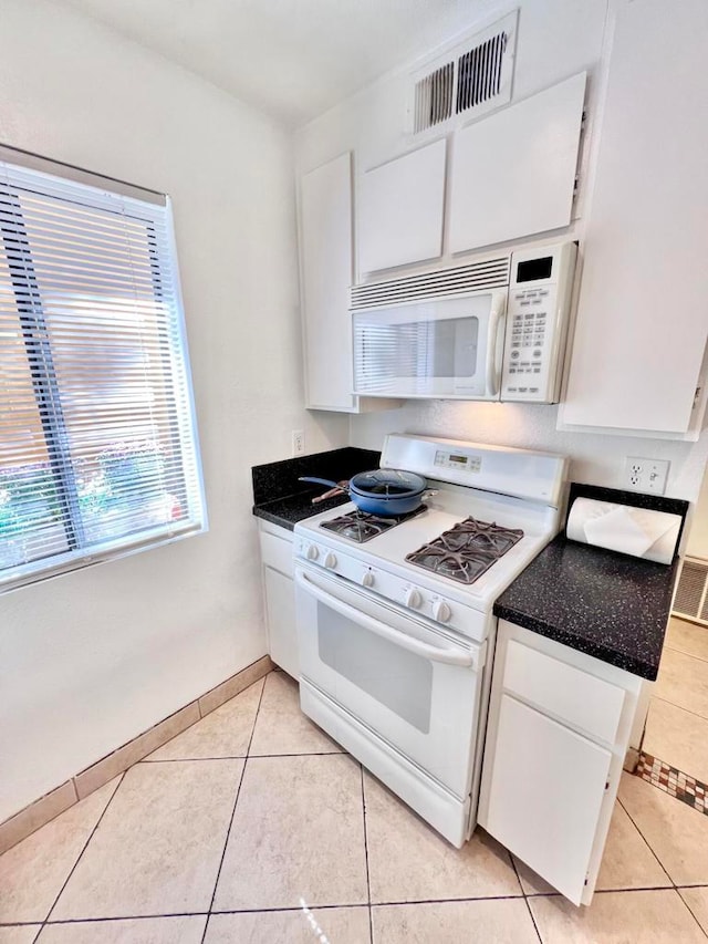 kitchen with light tile patterned flooring, white appliances, and white cabinetry