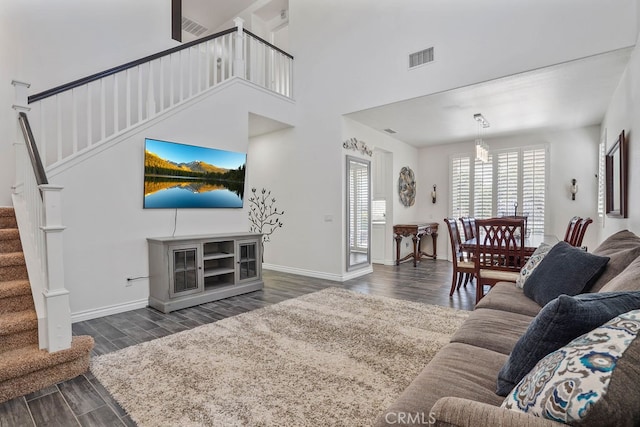 living room featuring a high ceiling, a notable chandelier, and dark hardwood / wood-style floors