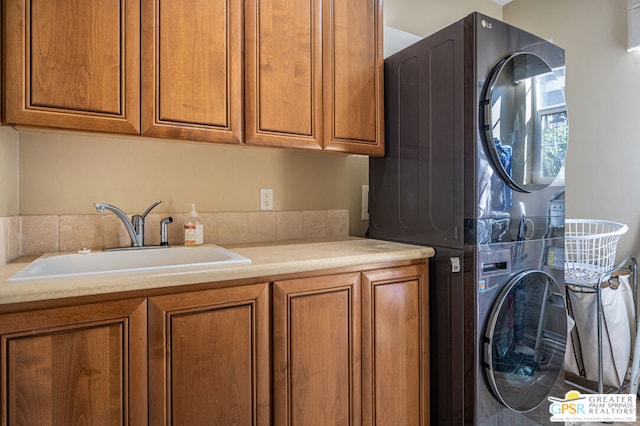 washroom featuring cabinets, stacked washer / drying machine, and sink