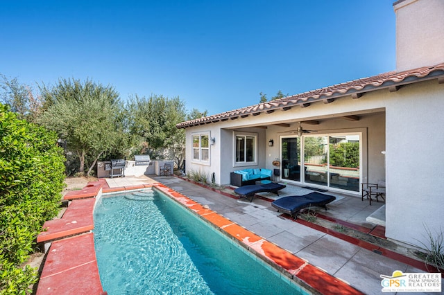 view of swimming pool featuring an outdoor living space, grilling area, an outdoor kitchen, ceiling fan, and a patio