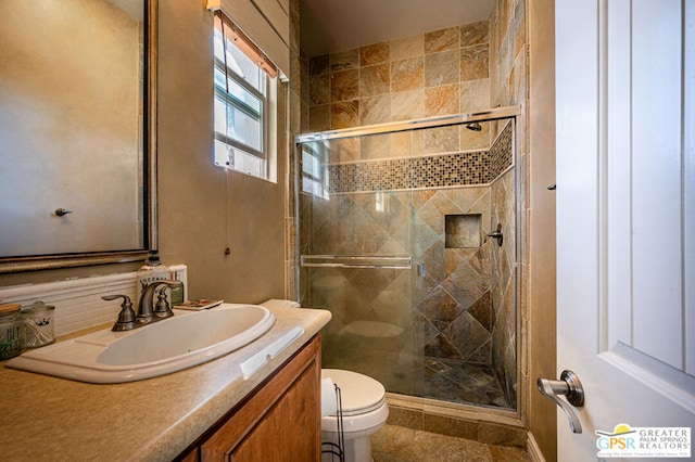 bathroom featuring vanity, toilet, and a shower with shower door