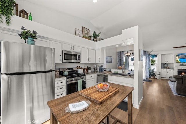 kitchen with white cabinetry, appliances with stainless steel finishes, lofted ceiling, wood-type flooring, and sink