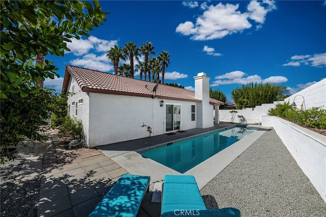 rear view of property featuring a fenced in pool and a patio