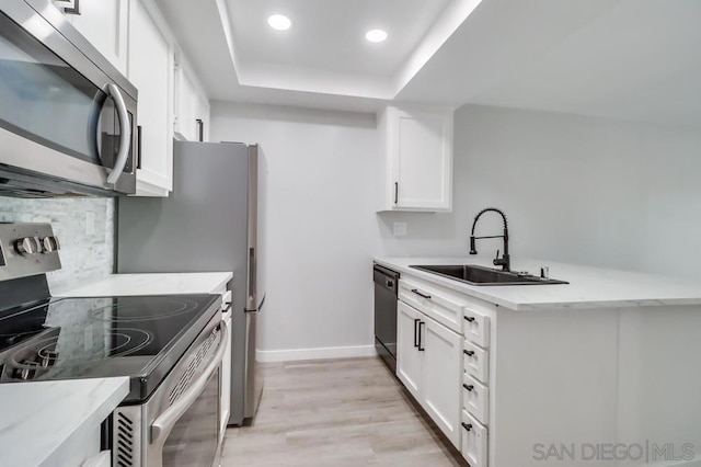 kitchen featuring sink, white cabinetry, stainless steel appliances, and light wood-type flooring