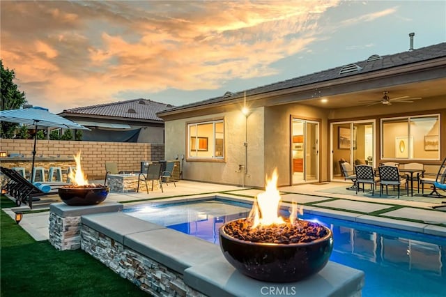 pool at dusk featuring a patio and an outdoor fire pit