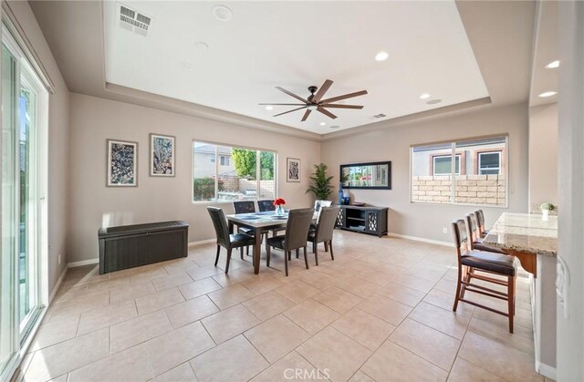 tiled dining area featuring a tray ceiling and ceiling fan