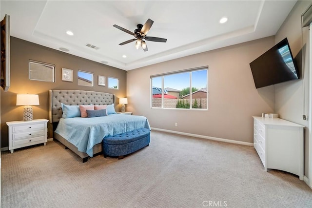 carpeted bedroom featuring a raised ceiling and ceiling fan