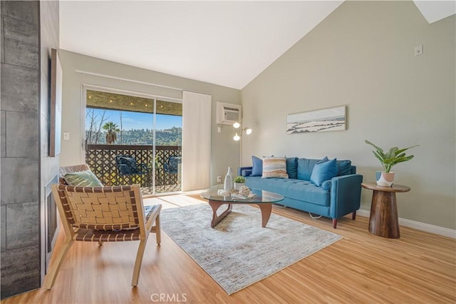 living room featuring light hardwood / wood-style floors, an AC wall unit, and high vaulted ceiling