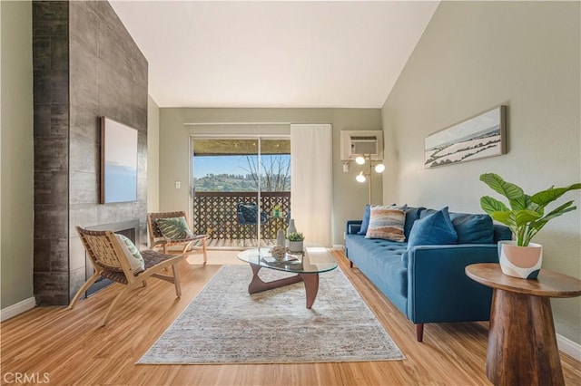 living room featuring light hardwood / wood-style flooring, lofted ceiling, and a wall unit AC