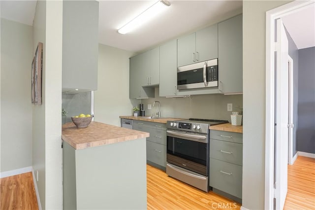 kitchen featuring stainless steel appliances, light hardwood / wood-style flooring, and sink