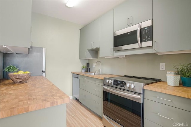 kitchen featuring appliances with stainless steel finishes, light hardwood / wood-style floors, gray cabinets, and sink