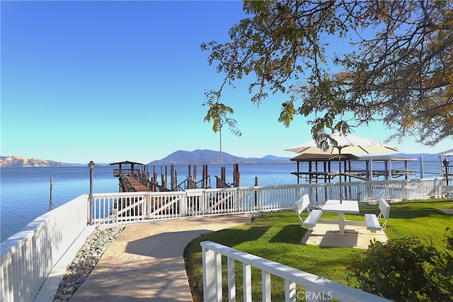 view of dock featuring a gazebo, a water and mountain view, and a lawn