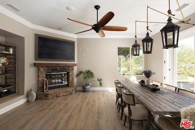 dining room with crown molding, hardwood / wood-style flooring, a fireplace, and ceiling fan