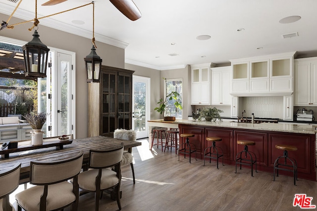 kitchen with ornamental molding, white cabinetry, light stone counters, and a breakfast bar area