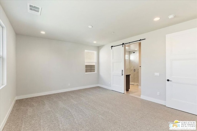 empty room featuring light carpet and a barn door