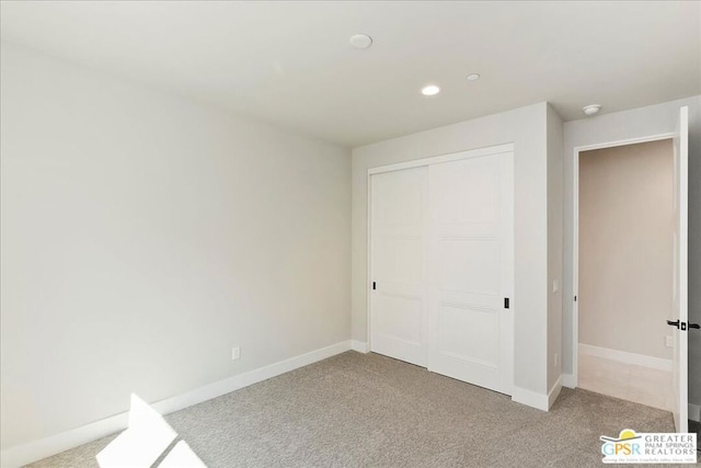 unfurnished bedroom with light colored carpet and a closet