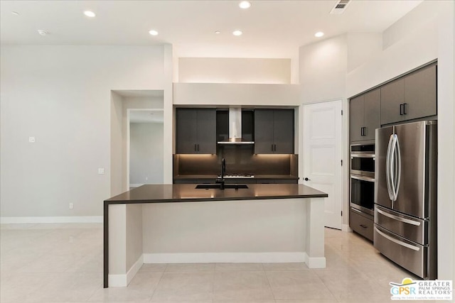 kitchen with wall chimney exhaust hood, stainless steel appliances, a center island with sink, sink, and light tile patterned floors