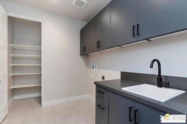 clothes washing area featuring hookup for a washing machine, sink, light tile patterned flooring, electric dryer hookup, and cabinets