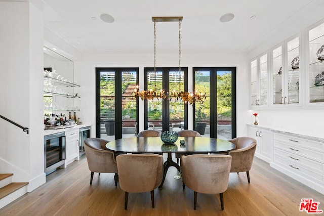 dining area featuring ornamental molding, wine cooler, light hardwood / wood-style flooring, and bar area