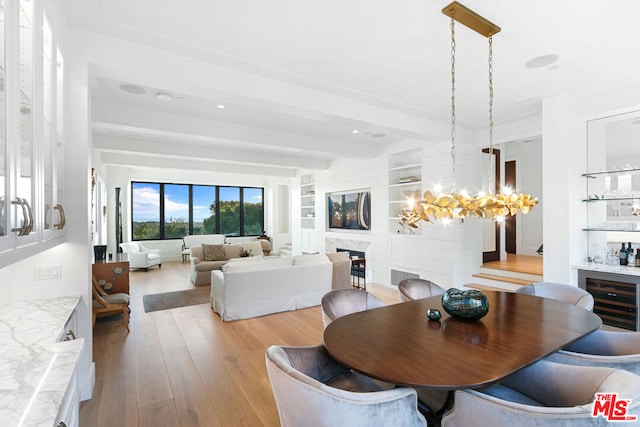 dining room featuring built in shelves, a chandelier, a premium fireplace, light hardwood / wood-style flooring, and wine cooler