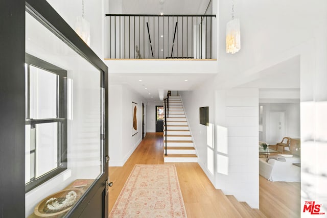 foyer entrance with light wood-type flooring and a towering ceiling