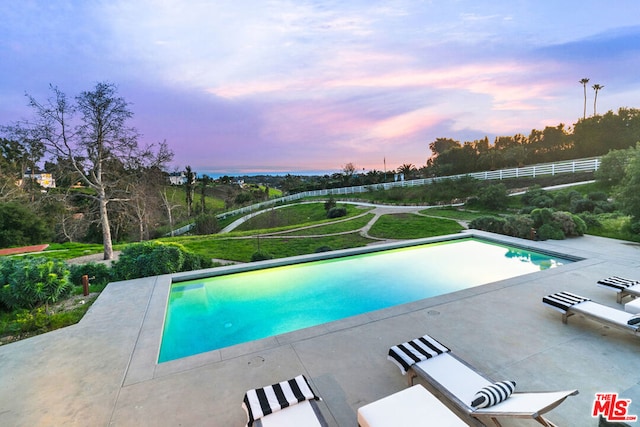 pool at dusk featuring a patio area