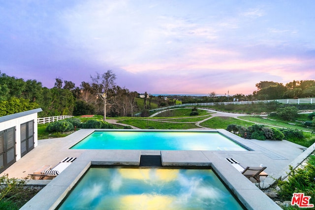 pool at dusk with a patio area