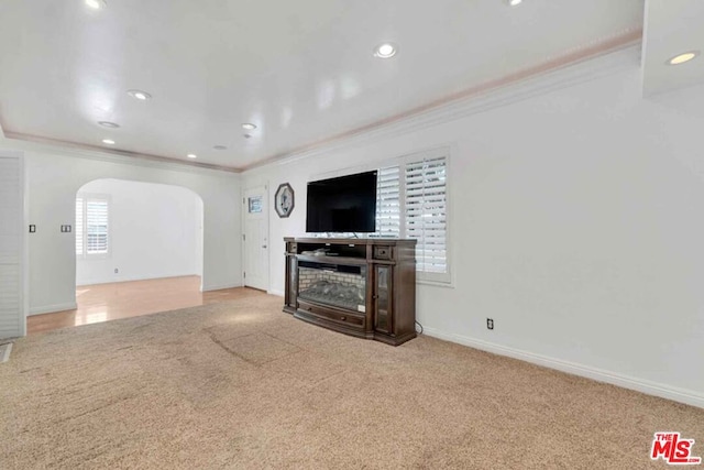 unfurnished living room featuring ornamental molding and light colored carpet